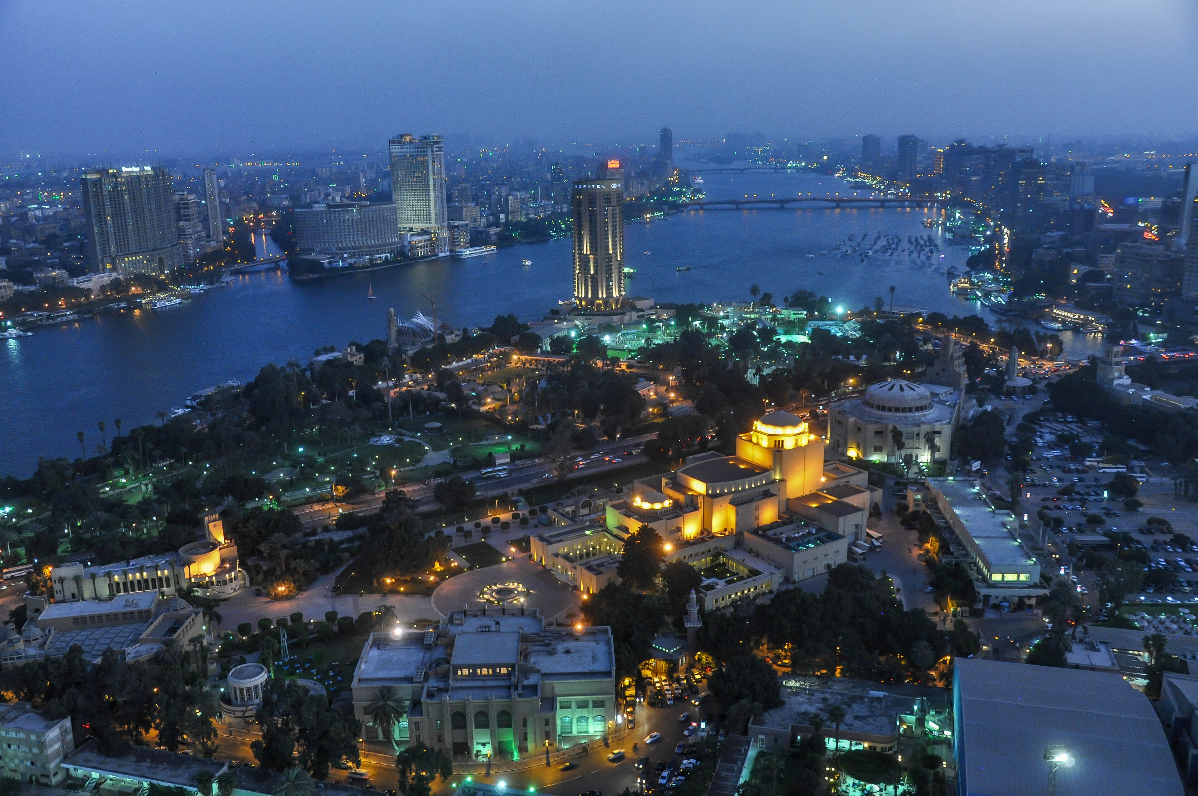 Aerial view of central Cairo at dusk, the Nile winding past the Sofitel tower and the Cairo Opera House lit against the darkening sky, 2015