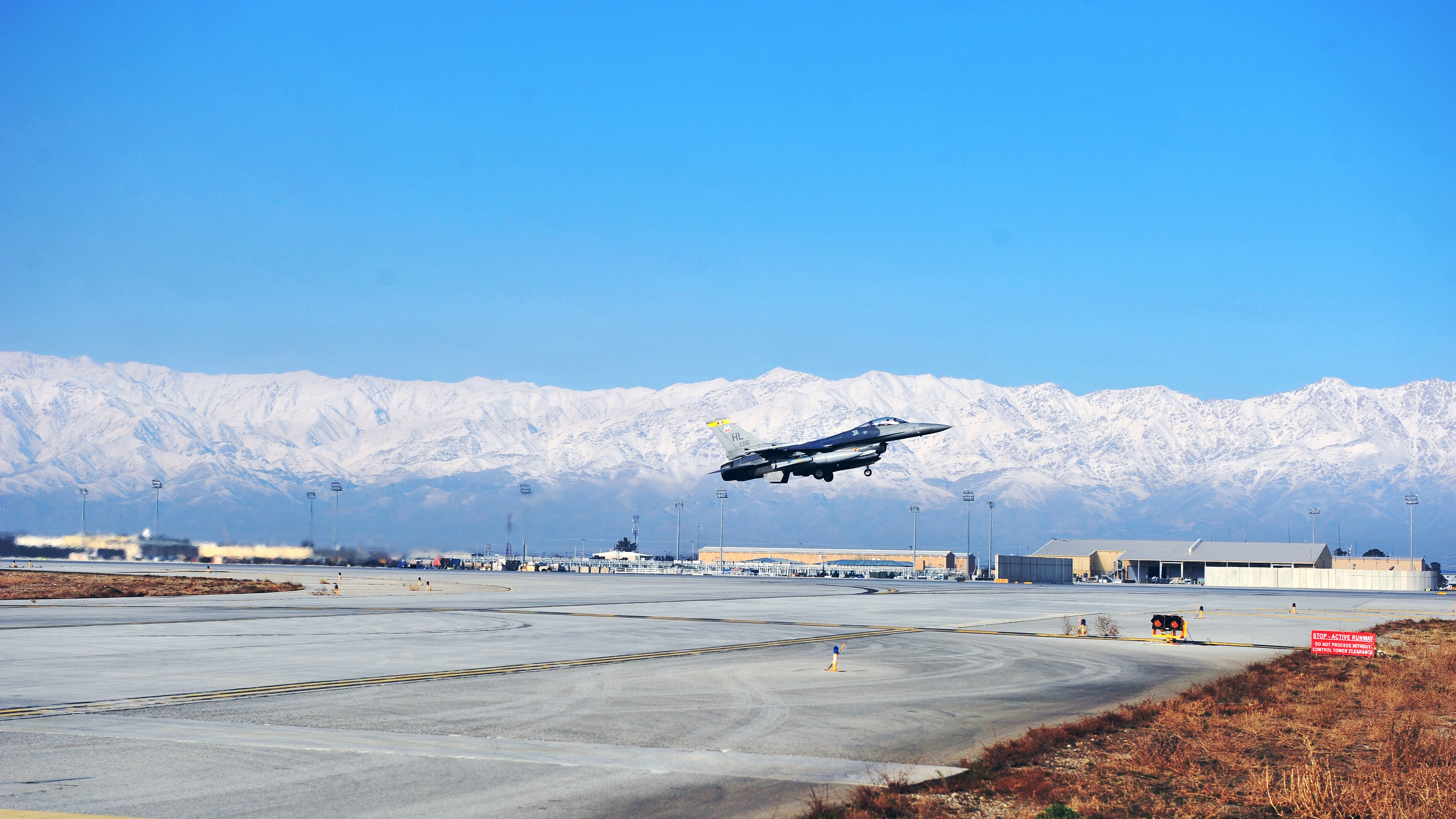 A US Air Force F-16 lifting off Bagram Airfield with the snow-capped Hindu Kush rising behind the runway, 2011
