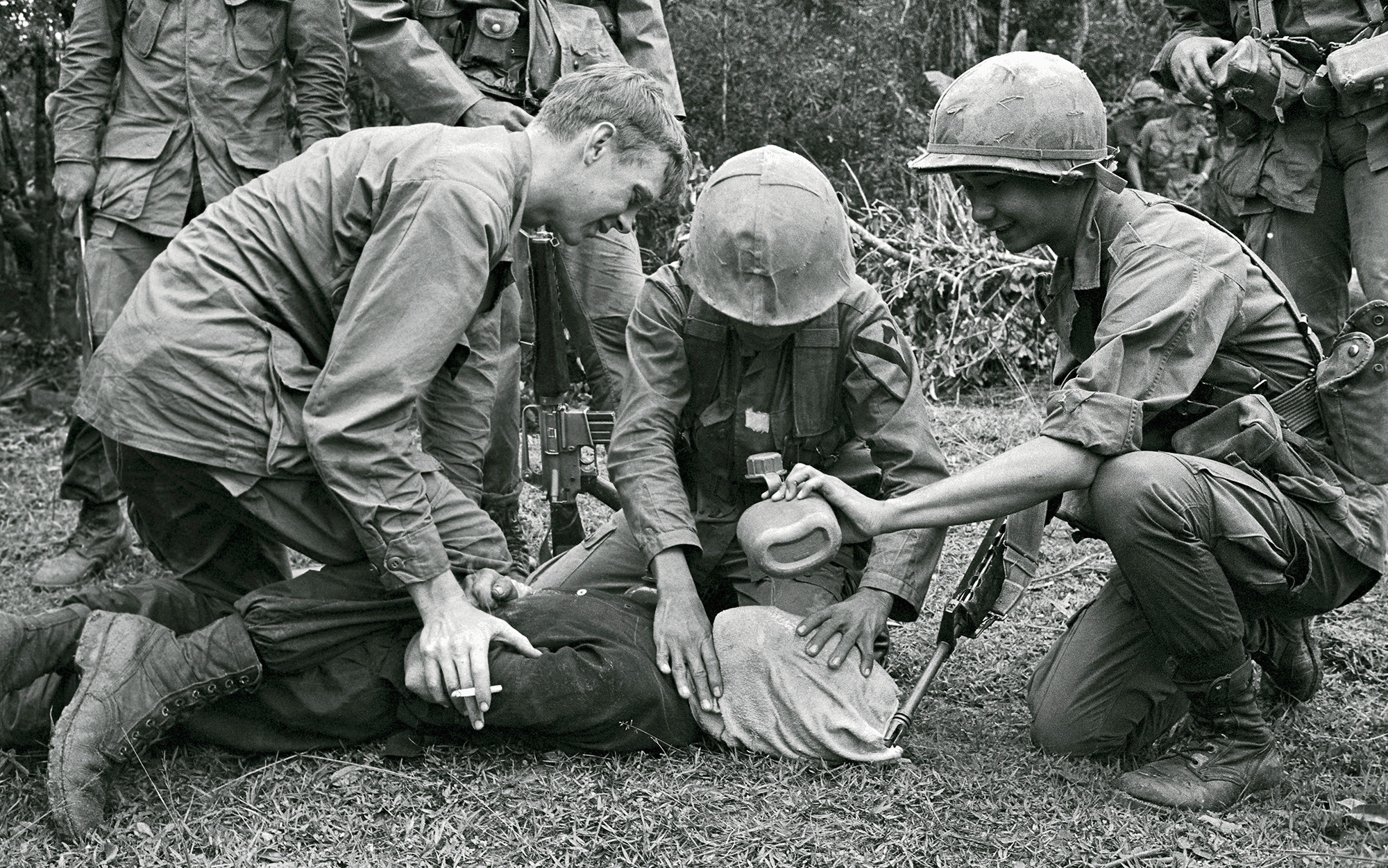 A black-and-white photograph of US and ARVN soldiers holding a Vietnamese prisoner down with a cloth over his face while pouring water from a jerrycan, 1968