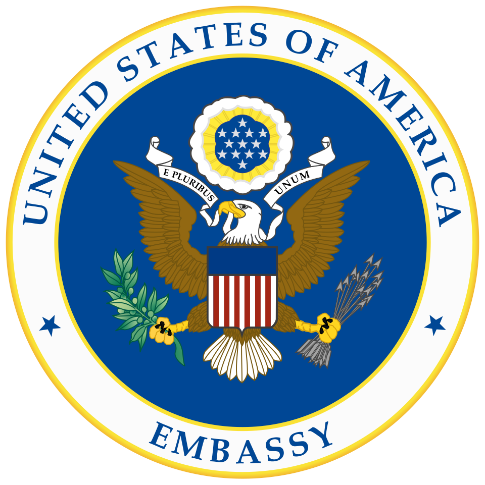 The circular seal of the US Embassy, bald eagle over the Great Seal shield ringed by the words United States of America Embassy, 1980