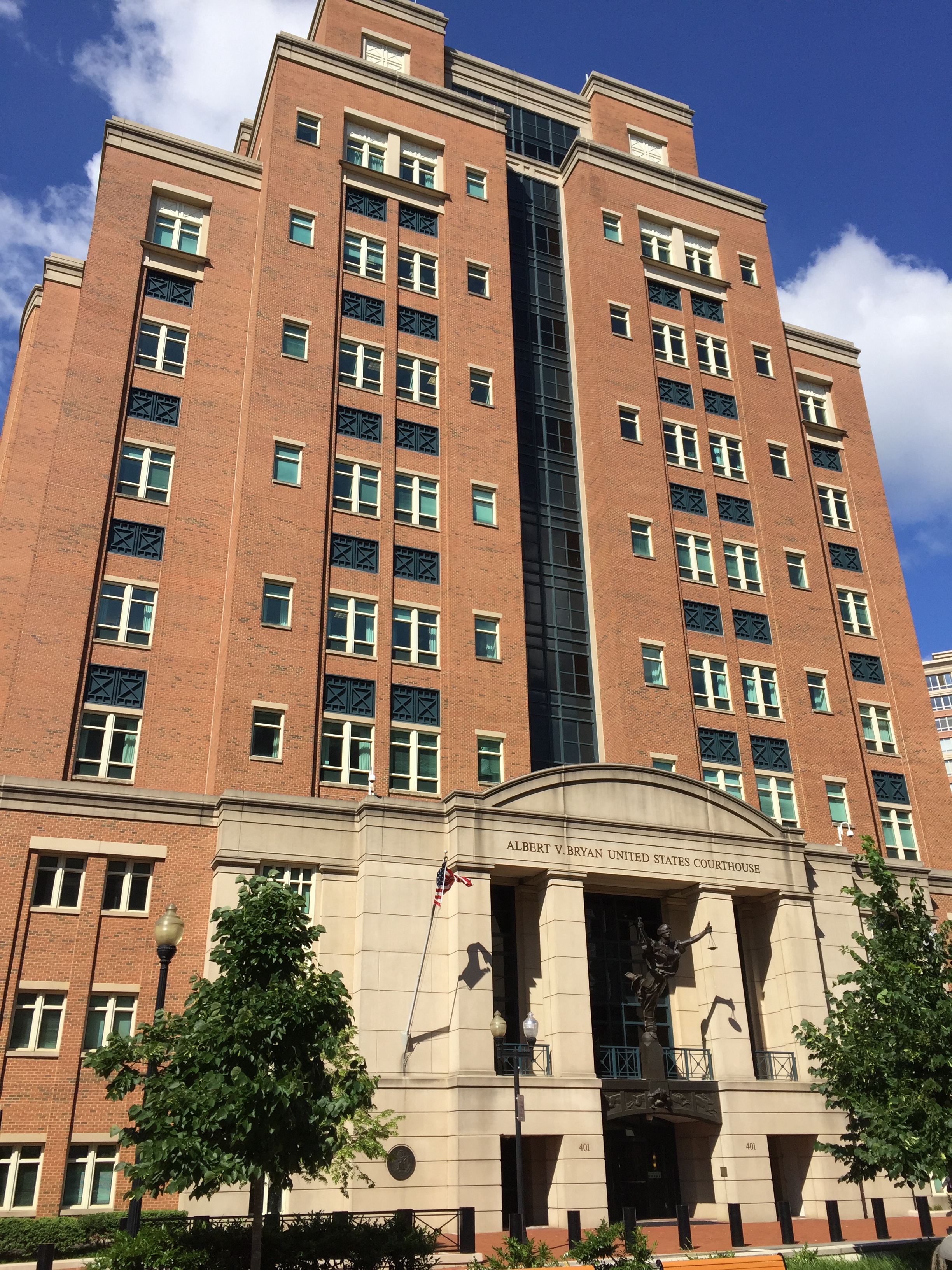 The Albert V. Bryan US Courthouse in Alexandria, brick tower rising over a stone entrance with a bronze figure of Justice, 2013