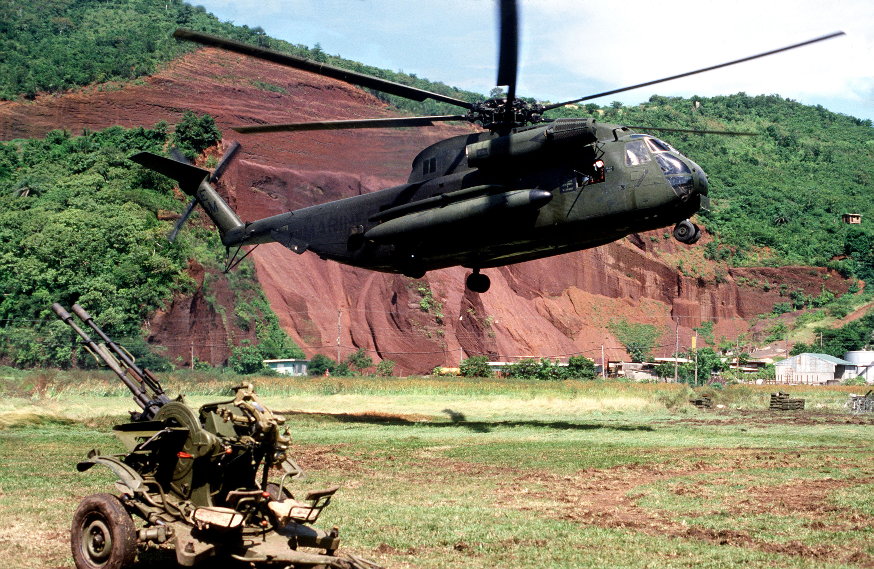 A US Marine CH-53 helicopter landing beside a captured anti-aircraft gun during Operation Urgent Fury on Grenada, 1983