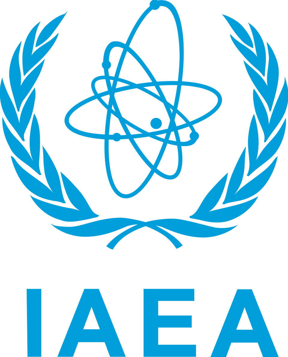The emblem of the International Atomic Energy Agency, a blue orbiting-atom motif inside a laurel wreath above the letters IAEA, 1957