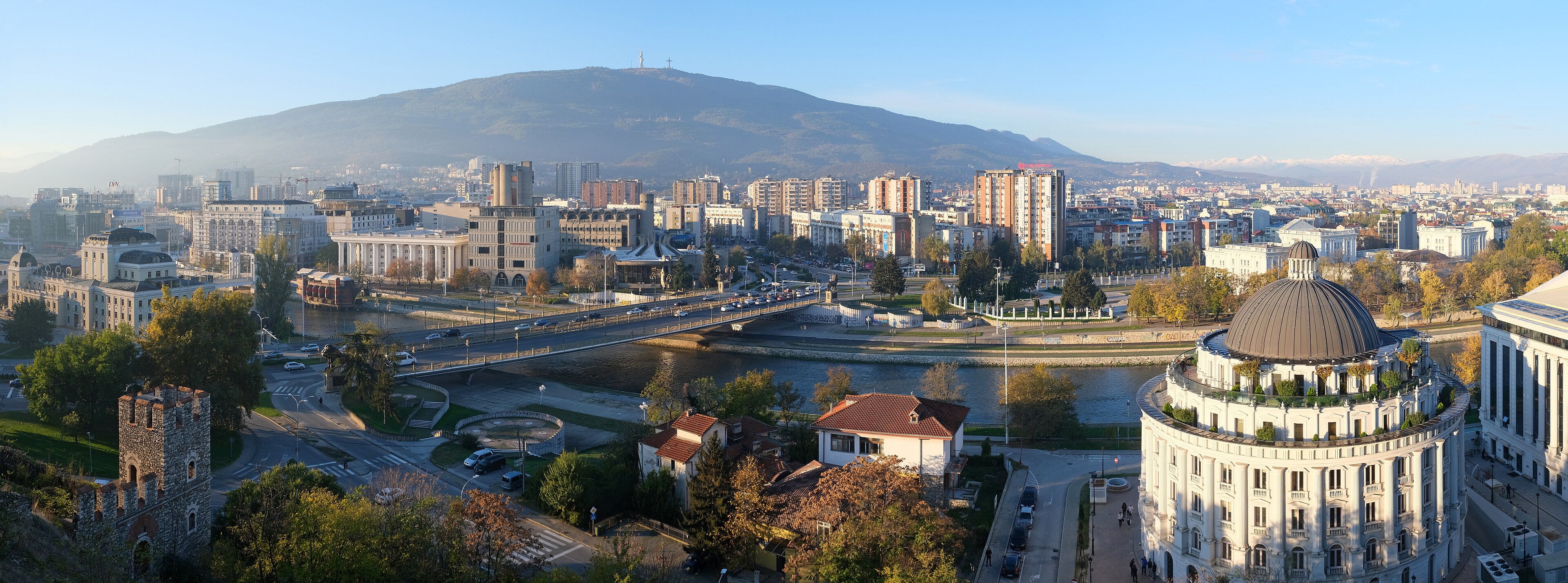 A panorama of central Skopje at dusk, the Vardar river winding under the Vodno mountain and its Millennium Cross, 2015