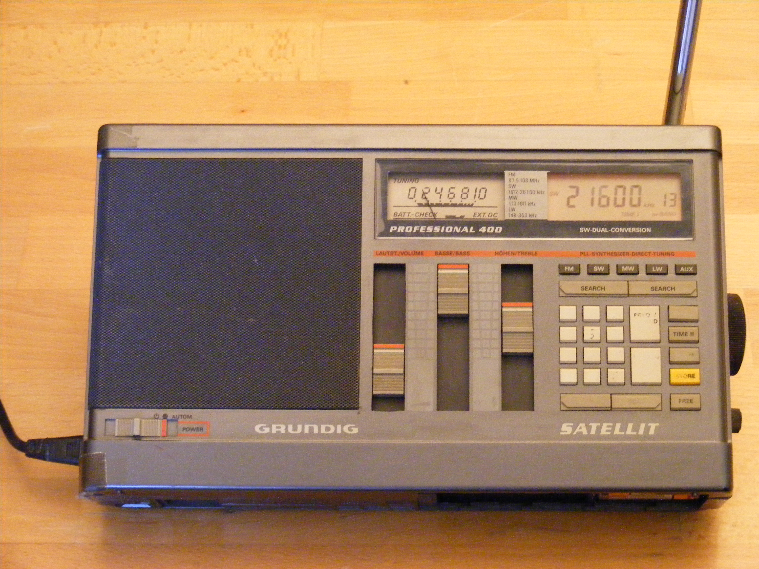A Grundig Satellit Professional 400 shortwave radio on a wooden table, tuning knob at 21,600 kilohertz with the aerial extended, 1985