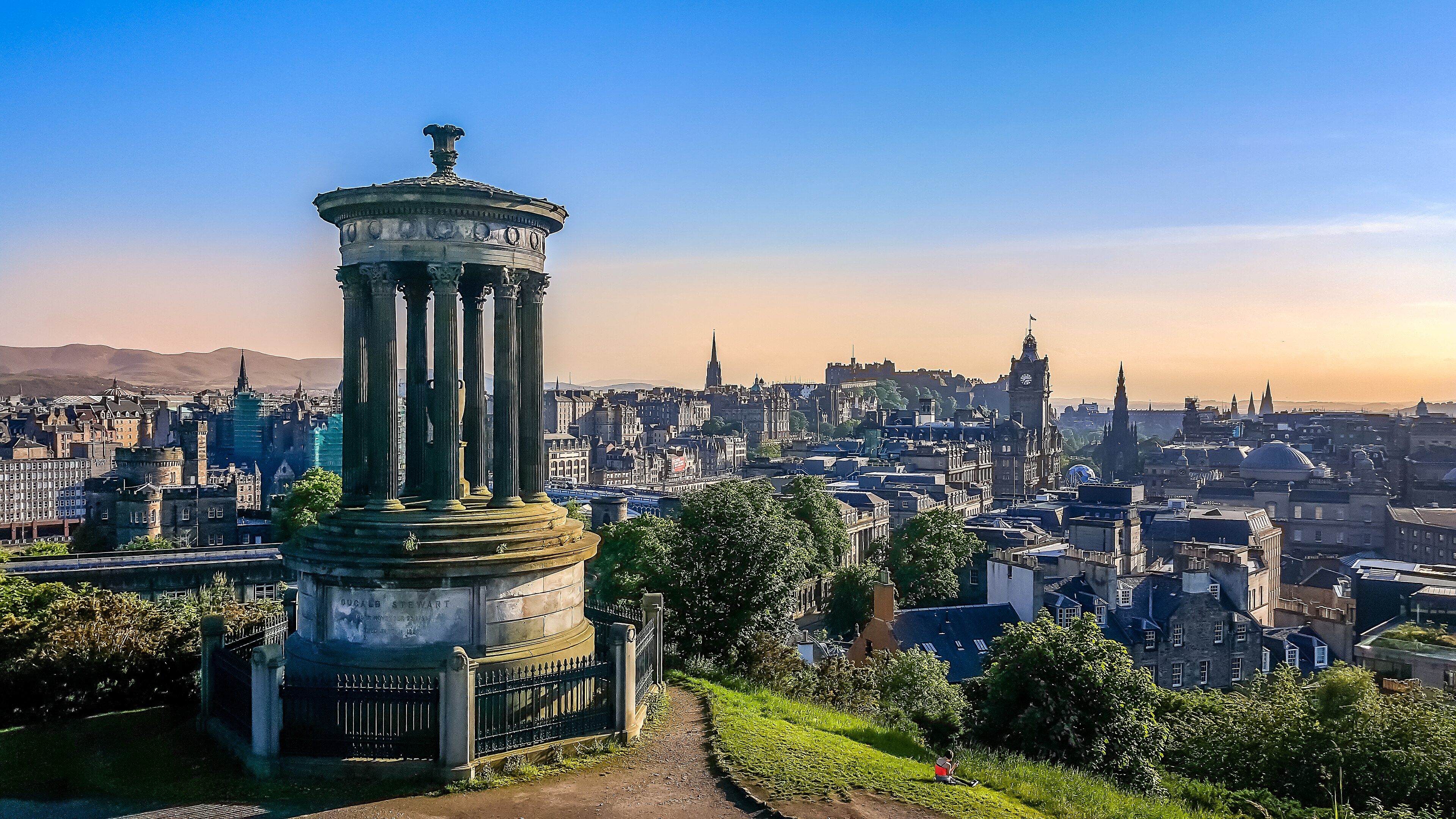 The Dugald Stewart Monument on Calton Hill above the Edinburgh skyline at dusk, the castle rock and clock tower in the distance under a purple sky, 2015