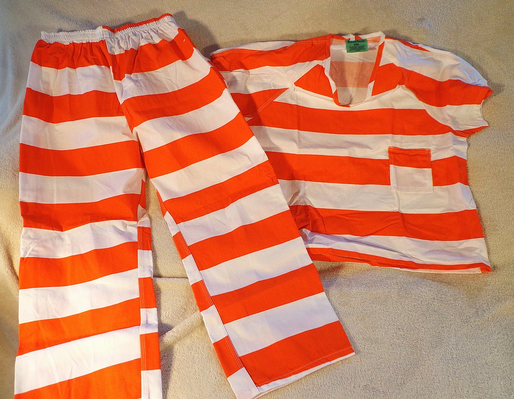 An orange-and-white striped prison shirt and matching trousers laid on a beige blanket, 2013