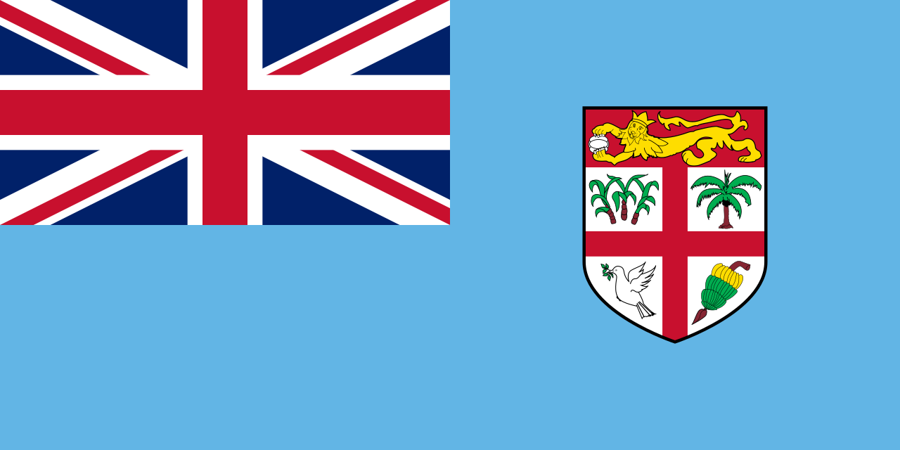The flag of Fiji, a Union Jack on a light-blue field with the Fijian coat of arms of a lion, palms, cocoa pod and dove on a red-cross shield, 1970