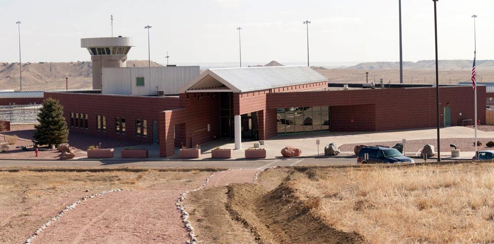 ADX Florence, low red-brick blocks under a stubby guard tower on the Colorado plain, 2013