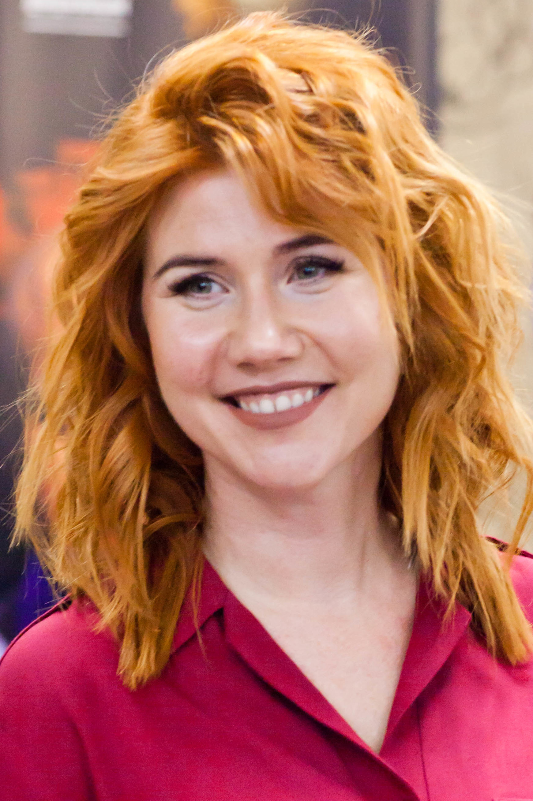 Anna Chapman smiling in a candid portrait, tousled red hair over a fuchsia collared shirt, 2010