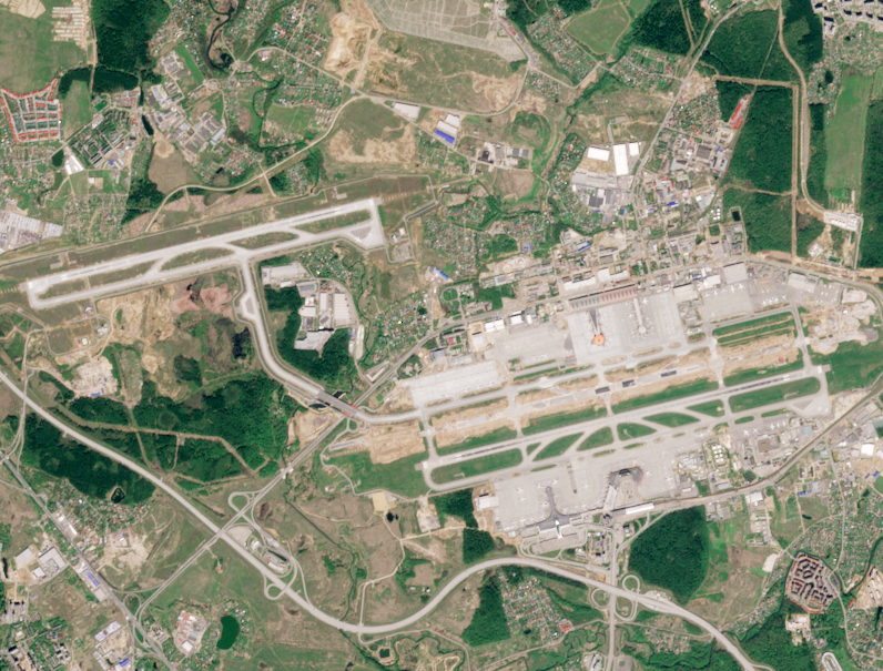 A satellite view of Sheremetyevo International Airport outside Moscow, three long runways and terminal fingers set among green Russian forest, 2013