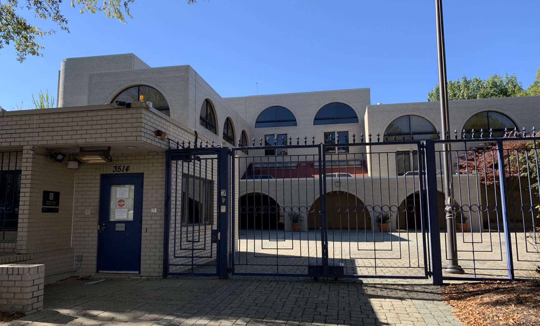 The white-brick Embassy of Israel at 3514 International Drive in Washington, arched windows and a blue iron gate below a spiked perimeter fence, 2015