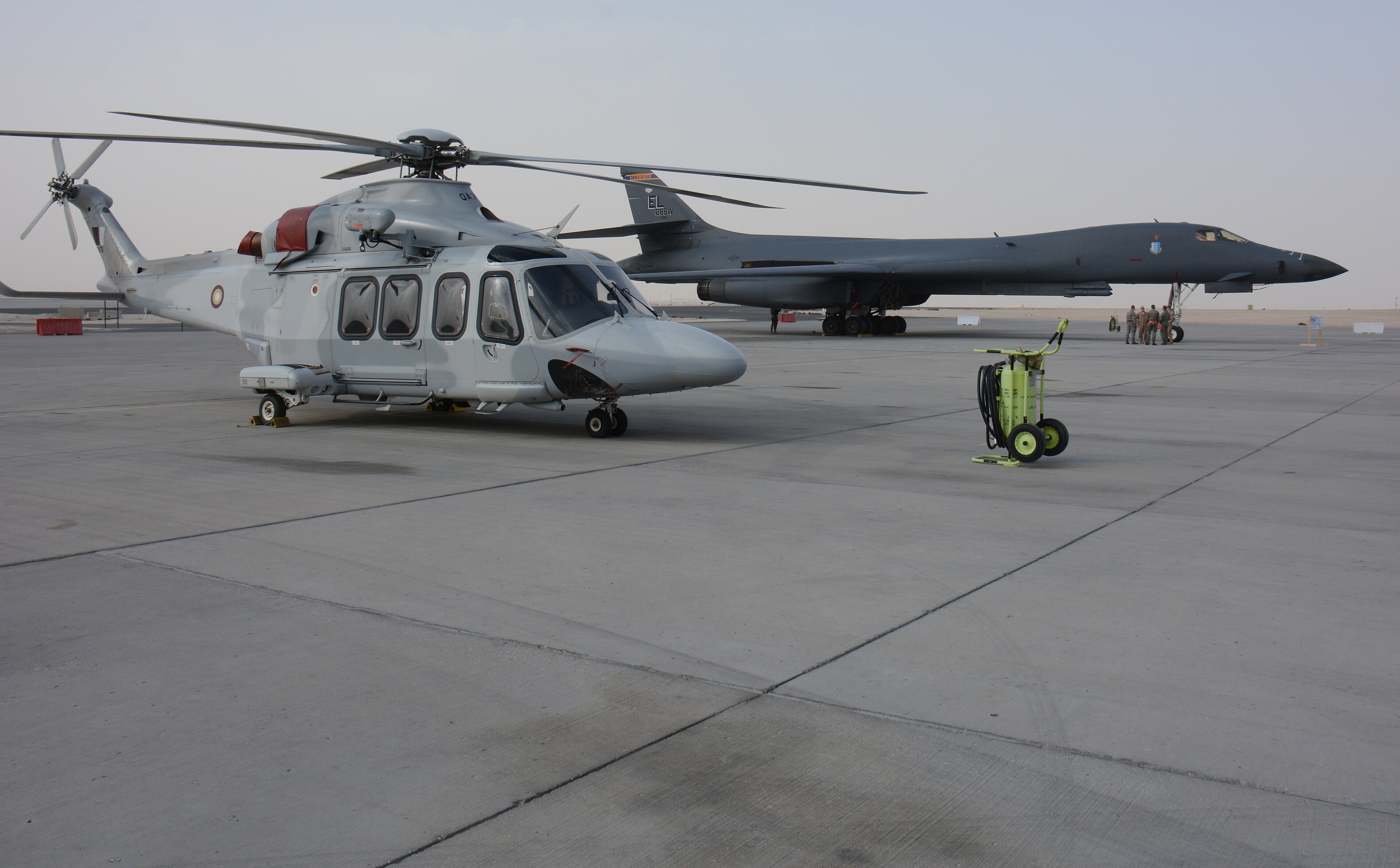A Qatari Air Force helicopter parked beside a US Air Force B-1B Lancer on the tarmac at Al Udeid Air Base, 2022