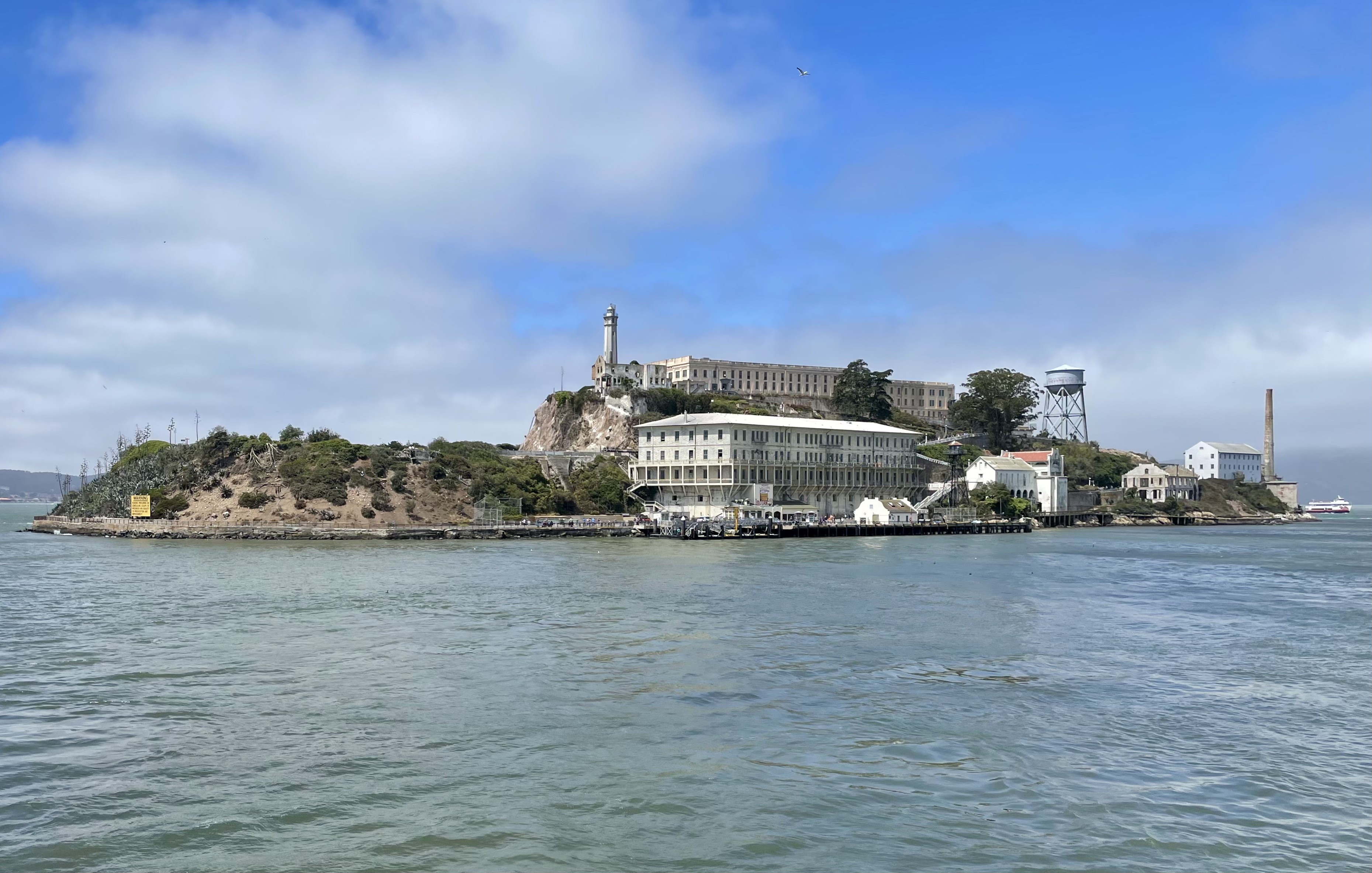 Alcatraz Island seen from the water, the lighthouse and cellhouse crowning the rock above the parade ground and the water tower, 2015