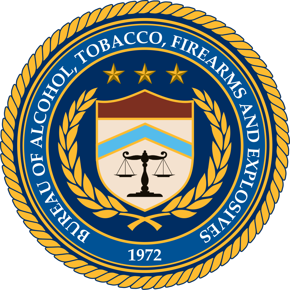 The seal of the Bureau of Alcohol, Tobacco, Firearms and Explosives, a shield with chevrons above the scales of justice ringed by a laurel wreath and the date 1972, 1972