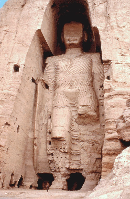 A standing Buddha of Bamiyan carved into the Afghan cliff face, a lone figure at its foot for scale, 1997