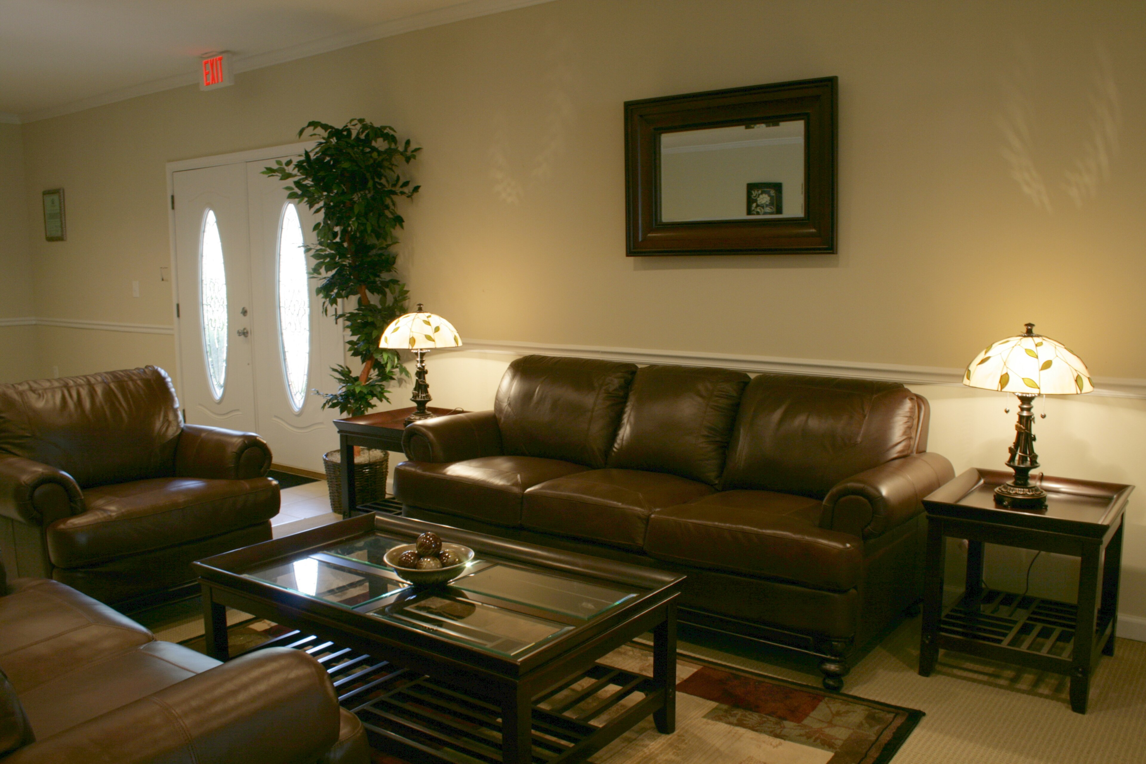 A living-room set with brown leather sofas around a glass-topped coffee table, 2015