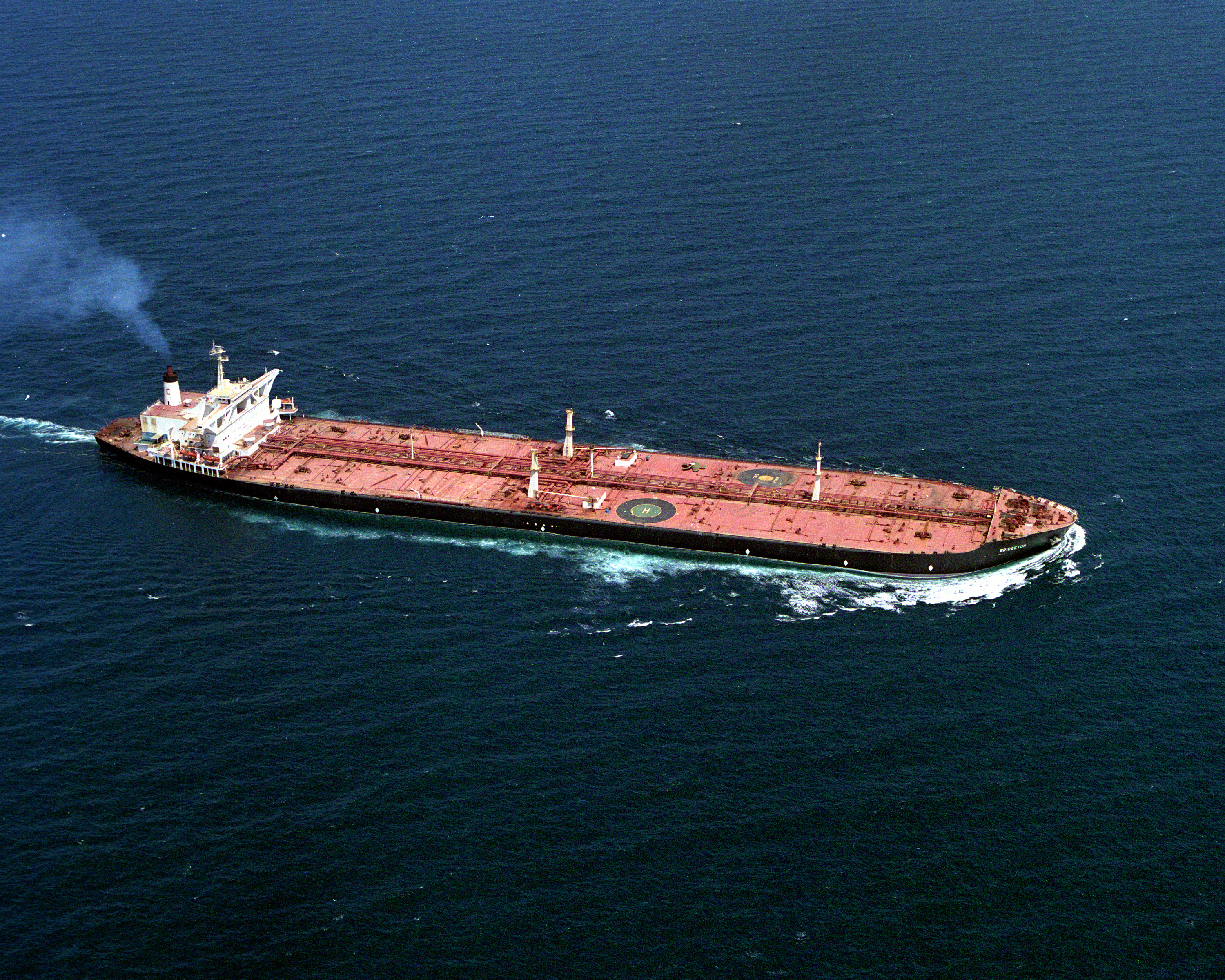 The supertanker SS Bridgeton under way in deep-blue open water, a red maindeck stretching between the white superstructure and the bow, 1987