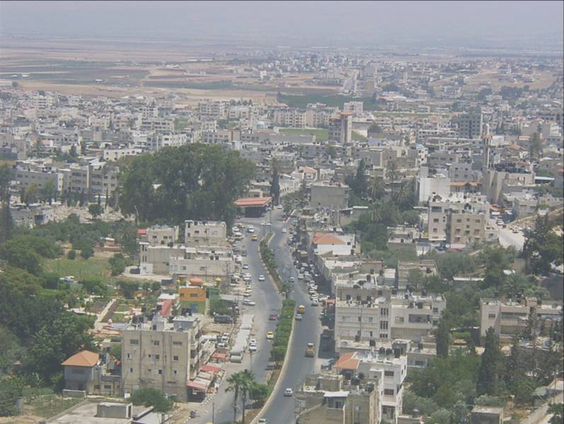 Rooftops of Jenin under a haze, dry hills of the northern West Bank rising behind the city, 2014