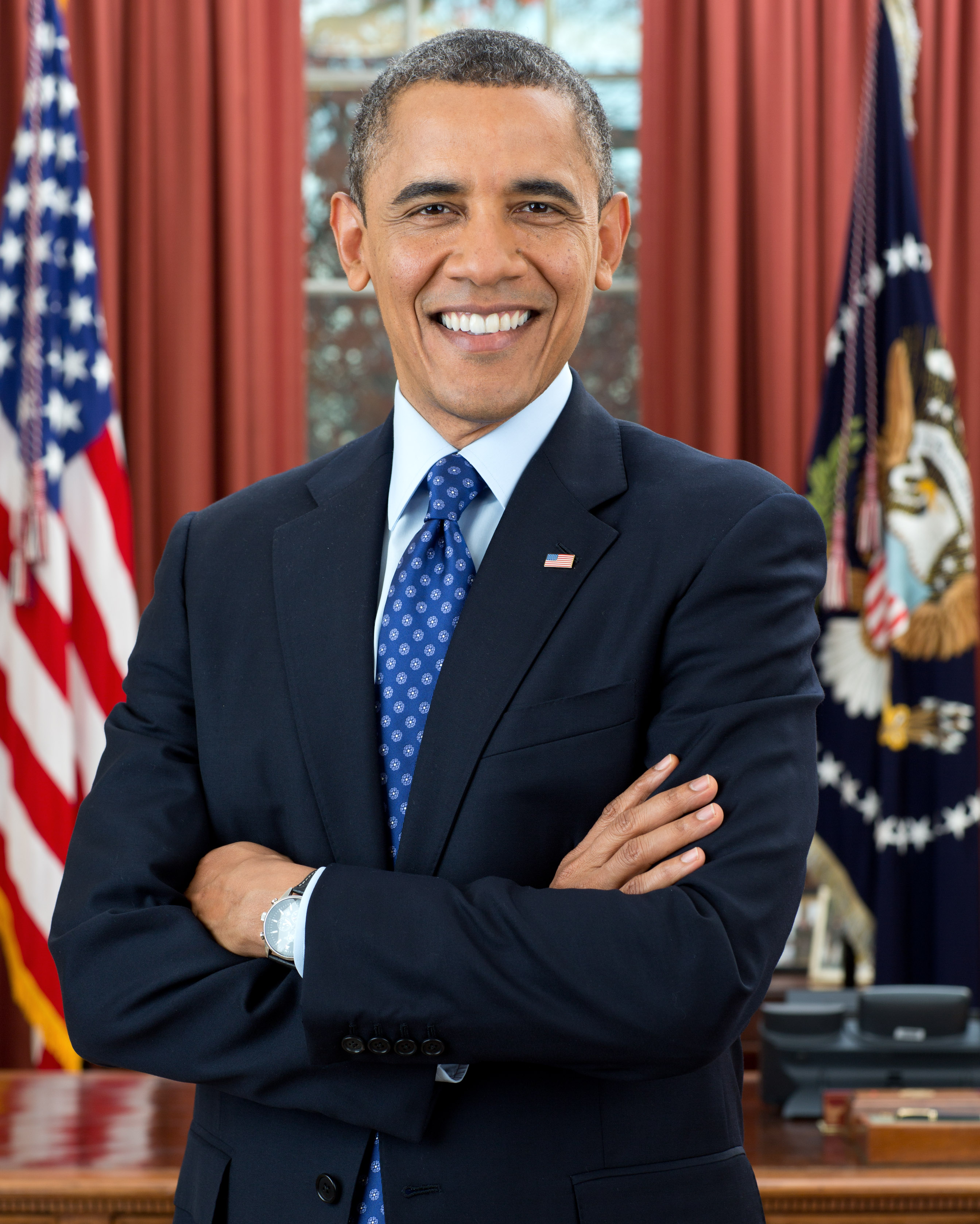 Barack Obama arms crossed in the Oval Office with the US flag and presidential flag flanking the red drapes behind him, 2012