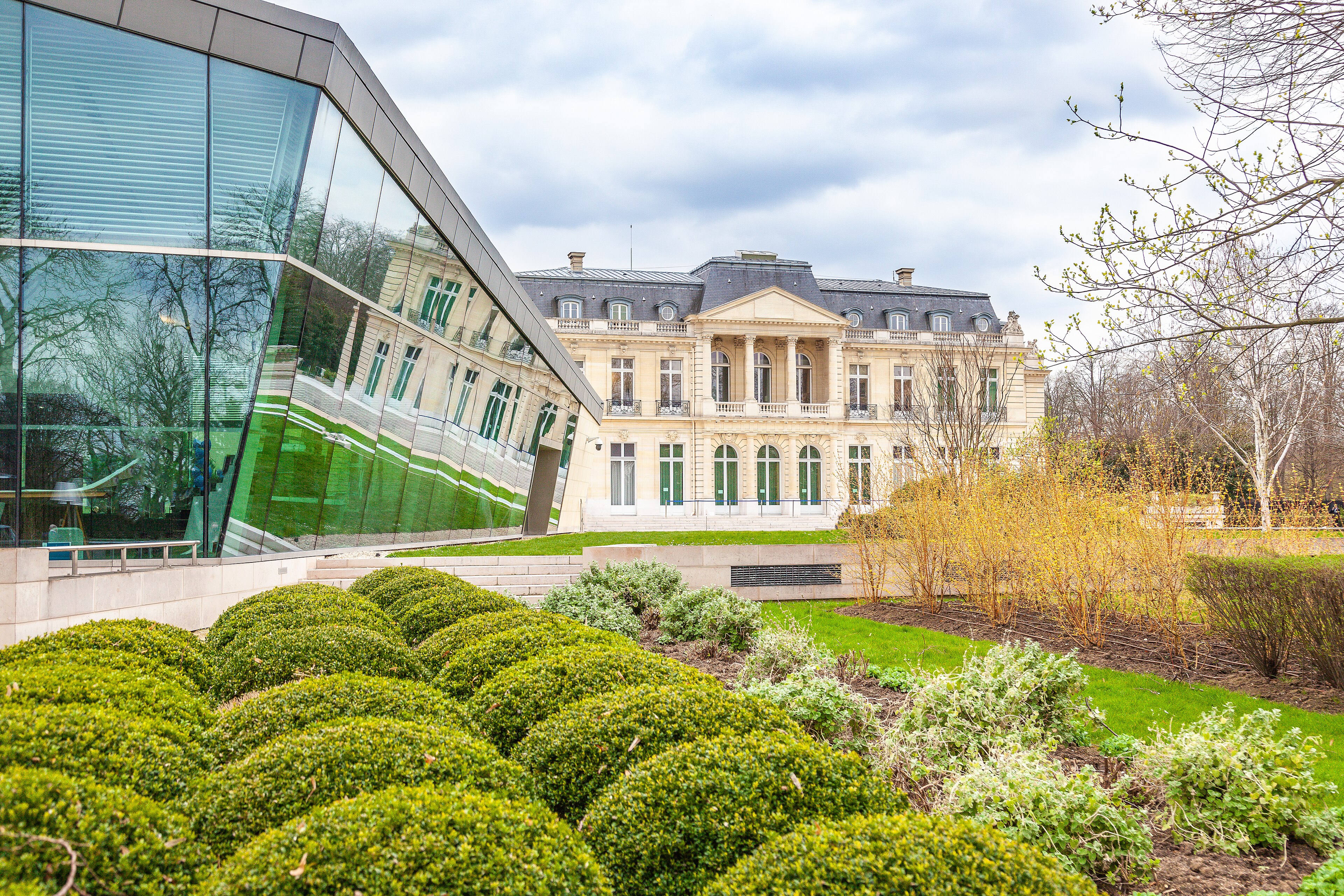 The Château de la Muette in Paris headquarters of the OECD, its cream stone façade beside a modern glass wing above trimmed gardens, 2019