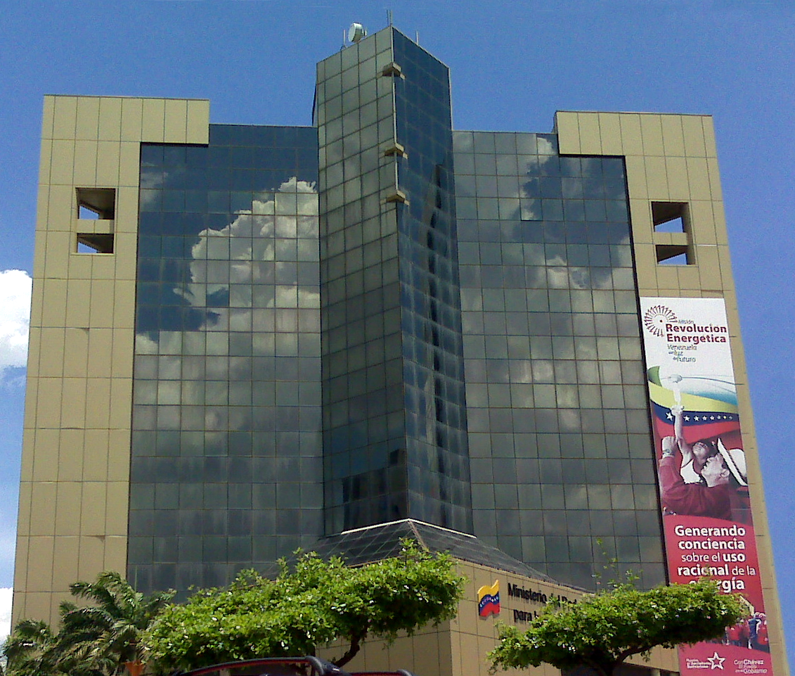 The mirrored-glass tower of the Venezuelan Ministry of Energy in Caracas, a Revolución Energética banner of Hugo Chávez raising a torch down its right flank, 2011