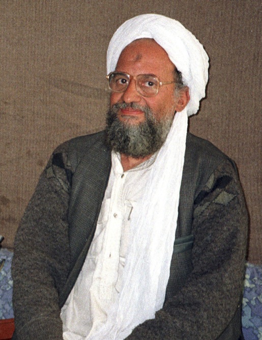 Ayman al-Zawahiri seated in a white turban and grey beard with gold-rimmed glasses, hands folded in his lap, 2001